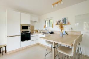 a kitchen with white cabinets and a wooden table at Appartement la Figurette vue mer in Théoule-sur-Mer