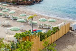 a beach with tables and chairs and umbrellas at Appartement la Figurette vue mer in Théoule-sur-Mer