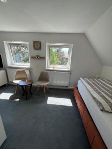 a bedroom with a bed and a table and two windows at Ferienhaus Cassel in Kassel