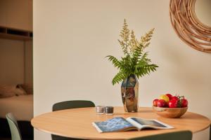 a wooden table with a vase and a bowl of fruit at Zeegser Duinen Suitelodges in Zeegse