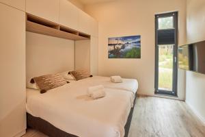 two beds in a room with a window at Zeegser Duinen Suitelodges in Zeegse