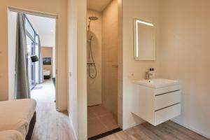 La salle de bains est pourvue d'un lavabo blanc et d'une douche. dans l'établissement Zeegser Duinen Suitelodges, à Zeegse