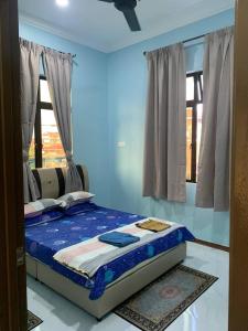 a bed in a room with a blue wall at Kastana Homestay II in Wakaf Baharu