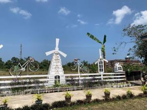 two white windmills and two bikes on a fence at Kastana Homestay II in Wakaf Baharu