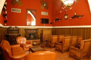 a living room with orange chairs and a fireplace at Hospederia del Real Monasterio in Guadalupe