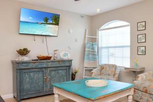 a living room with a table and a tv on the wall at The Palms 2B by Pristine Property Vacation Rentals in Mexico Beach