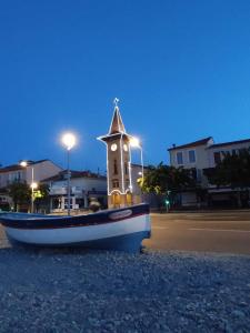 un pequeño barco sentado en la playa con una torre de reloj en Lovely Studio & Garden - près des plages Cagnes-sur-Mer, en Cagnes-sur-Mer