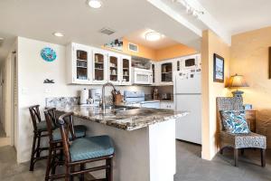 a kitchen with white cabinets and a counter with chairs at Casa De Emdeko 324 in Kailua-Kona