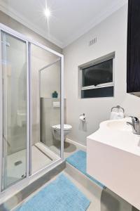 a bathroom with a shower and a sink and a toilet at Spray Lodge in Bloubergstrand