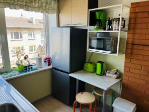 a kitchen with a refrigerator and a table with a microwave at Maria Apartment at Rootsi street in Kuressaare