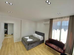 um quarto com uma cama, um sofá e uma janela em Mara Central Apartment 4 em Tirana