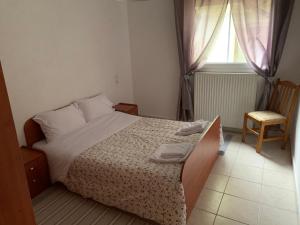 - une chambre avec un lit, une fenêtre et une chaise dans l'établissement Ο ΦΟΙΝΙΚΑΣ ΣΤΗΝ ΚΑΣΤΟΡΙΑ, à Kastoria