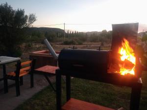 a barbecue grill with a fire in a field at Espectacular Cabaña En Valle Grande Terraza Panorámica 360 in Valle Grande