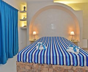 Schlafzimmer mit einem Bett mit blauen und weißen Streifen in der Unterkunft TINOS AQUA PALAZZO in Tinos