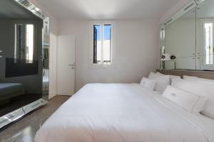 a white bedroom with a large bed and a tv at G House in Venice