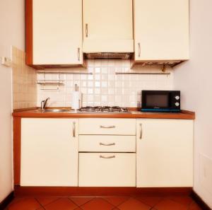 eine Küche mit weißen Schränken, einer Spüle und einer Mikrowelle in der Unterkunft Il Lusso Della Semplicità in Piacenza