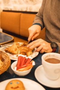 パリにあるラ メゾン モンパルナスのコーヒーと一緒にテーブルの上でサンドイッチを食べる人