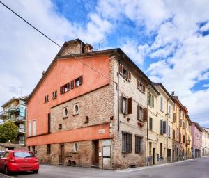 ein rotes Auto, das vor einem Backsteingebäude parkt in der Unterkunft Il Lusso Della Semplicità in Piacenza