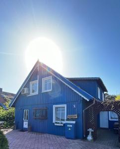 Una casa azul con el sol detrás. en Bangomūša en Nida