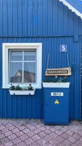 a blue building with a window and two plants on it at Bangomūša in Nida