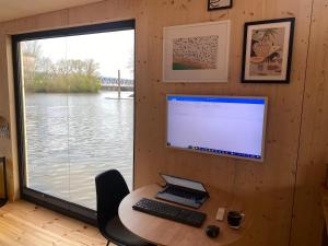 a computer sitting on a desk with a window at Hausboot OFF im Diamantgraben an der Elbe in Hamburg