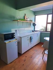a kitchen with white appliances and a table and a window at Rondebosch Cottage in Cape Town +6 photos