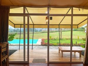 a patio with a large umbrella and a bench at Buana Glamping in Pengalengan