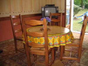 einen Esstisch mit Stühlen, einem Tisch und einem TV in der Unterkunft La chataîgneraie 