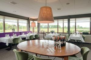 un ristorante con tavoli e sedie e bottiglie di vino di Golf Lodge a Zeijerveen