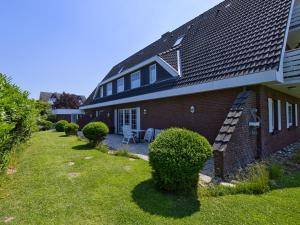 a house with a yard with bushes and a roof at BUE Appartementhaus Seewind in Büsum