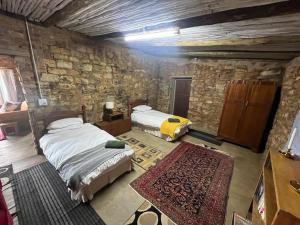 a bedroom with two beds and a stone wall at Kwaggaskop Farm Kliphuis in Dullstroom