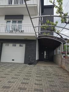 a house with a garage with a white garage door at Apartman Juric in Posušje