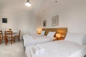 a hotel room with two beds and a table at Fysalida's Coastal Gem 4 - Steps Away from the Sea in Heraklion