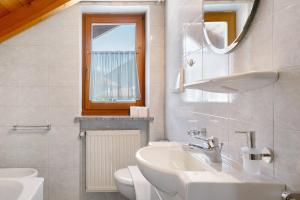 uma casa de banho branca com um lavatório e um espelho em Mayr Apartments Fünf em Plaus
