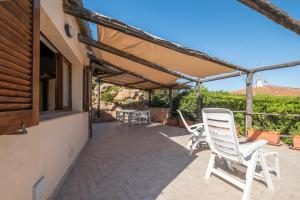 patio con sedie bianche e pergolato di Discesa a Mare-Villa Esclusiva Vista Caprera a Casale Azara Altre 24 foto