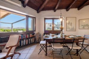 una sala da pranzo con tavolo, sedie e finestre di Discesa a Mare-Villa Esclusiva Vista Caprera a Casale Azara