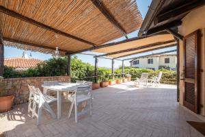 patio con tavolo e sedie sotto un pergolato in legno di Discesa a Mare-Villa Esclusiva Vista Caprera a Casale Azara