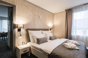 een slaapkamer met een groot bed en 2 handdoeken bij ARIETES MARMONT Resort in Tatranska Strba