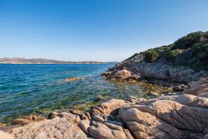 un gruppo di rocce sulla riva di un corpo idrico di Discesa a Mare-Villa Esclusiva Vista Caprera a Casale Azara