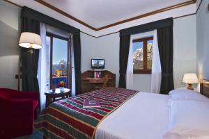 um quarto de hotel com uma cama e uma janela em Boutique Hotel Villa Blu Cortina D'Ampezzo em Cortina dʼAmpezzo