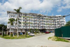 a large white building with palm trees in a parking lot at 1 bedroom with balcony near airport in Mactan