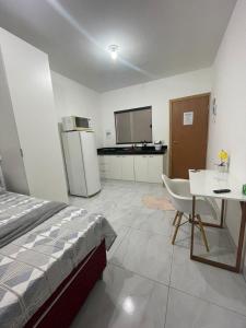 a bedroom with a bed and a table and a refrigerator at Flat completo Aparecida de Goiânia in Aparecida de Goiania