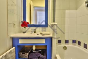 a bathroom with a sink and a mirror and a tub at LocaLise - A18 - Appartement avec balcon - Petite vue mer à travers le palmier - Piscine de avril à septembre - Wifi inclus - Animaux admis - Draps inclus - Parking inclus in Le Guilvinec +25 photos