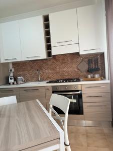 een keuken met witte kasten en een tafel en een stoel bij a casa di Lalla in Borgo Podgora