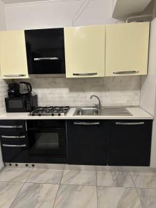 una cocina con armarios en blanco y negro y fregadero en Renthouse Apartments - Feel Like Home, en Chişinău