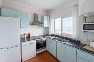 cocina con armarios azules, fregadero y ventana en Vista Arenal, en Arenal d'en Castell