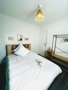 uma cama branca num quarto com luz em Appartement cosy avec terrasse et parking, 4 pers. em Étampes