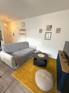 uma sala de estar com um sofá e uma mesa em Appartement cosy avec terrasse et parking, 4 pers. em Étampes