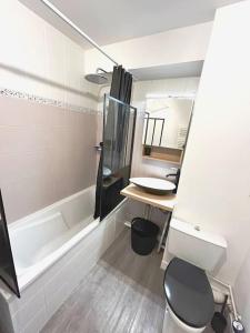 uma casa de banho com uma banheira, um lavatório e um WC. em Appartement cosy avec terrasse et parking, 4 pers. em Étampes