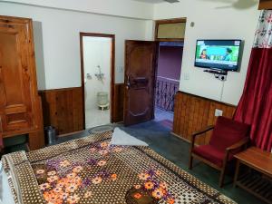 HOTEL UNIQUE في مانالي: غرفة نوم بسرير وتلفزيون على جدار